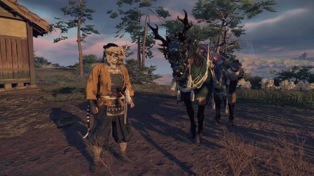 Screenshot from Ghost of Tsushima, showing a samurai standing next to his horse. The samuari is wearing armor with a breastplate and loose flowing fabric for ease of modement. His mask is shaped like one of the colossi from Shadow of the Colossus. The horse is wearing armor with an elaborate headpiece with antlers, like a cross between a dragon and a stag.